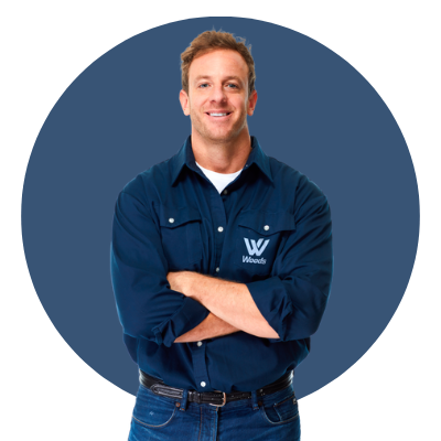 A friendly young man wearing a navy blue uniform shirt with Woods Air Movement embroidered on the chest pocket