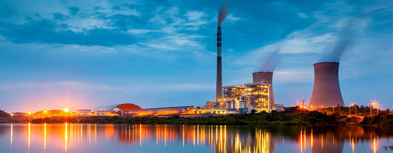 A sunrise banner photo of a power station next to still water