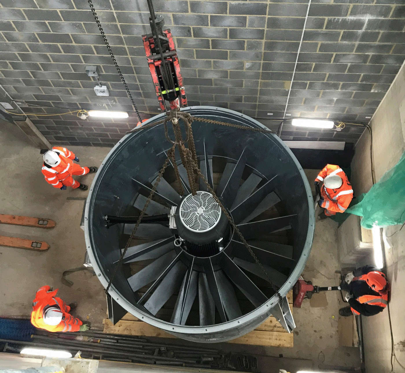 A photo showing a huge axial fan being lowered into position by a crane at Nine Elms station