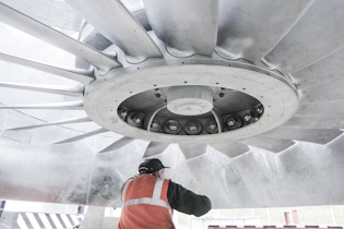 Photos shows a man in a hi-vis orange vest working on a large new axial fan