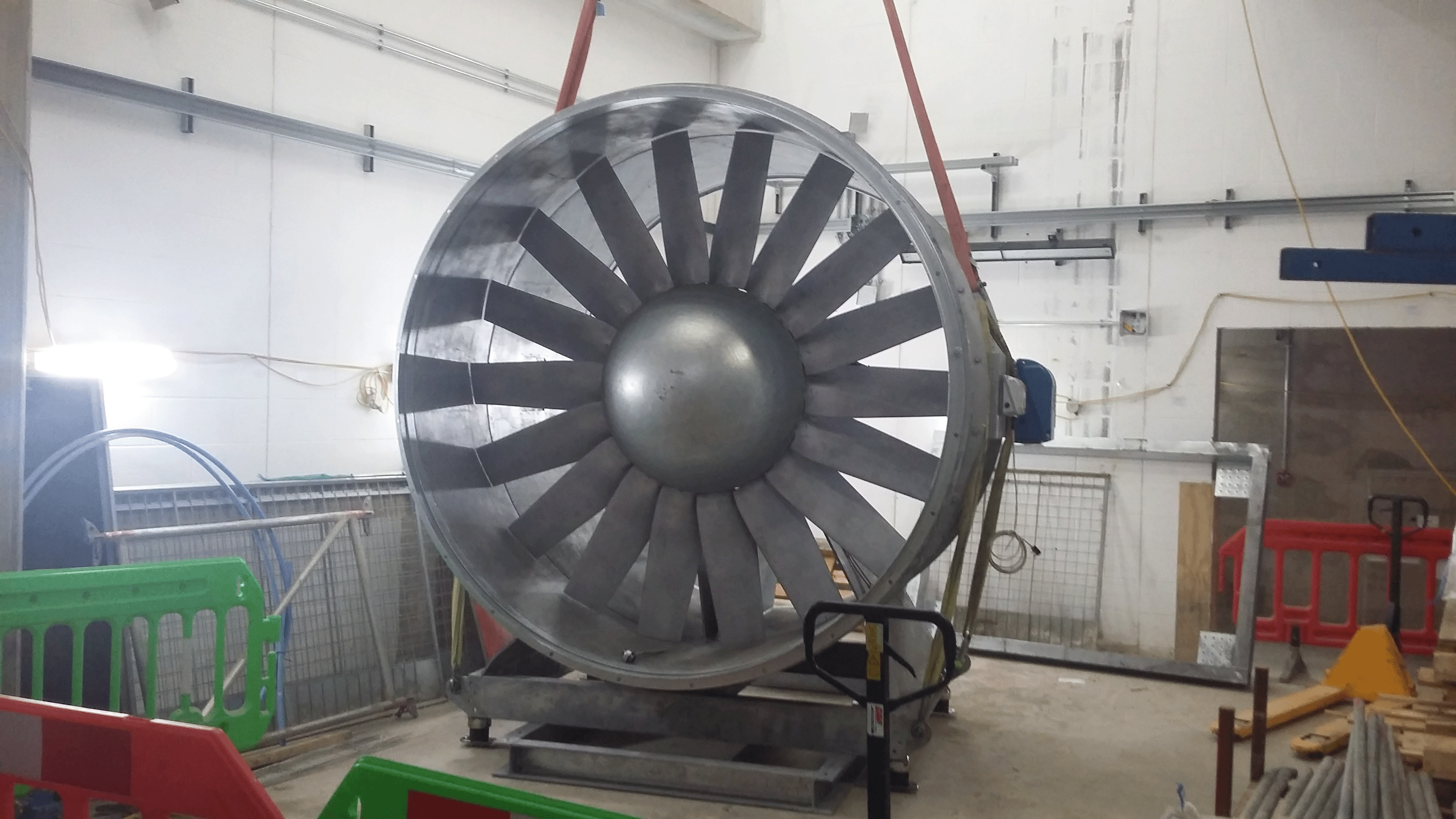 A photo shows a Wood axial fan being lowered into place by a crane