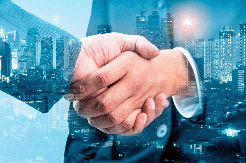 A stock image of two business men shaking hands with a city scene overlaid across the background