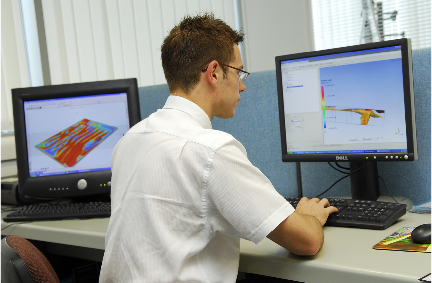A young man working at a computer running a CFD simulation