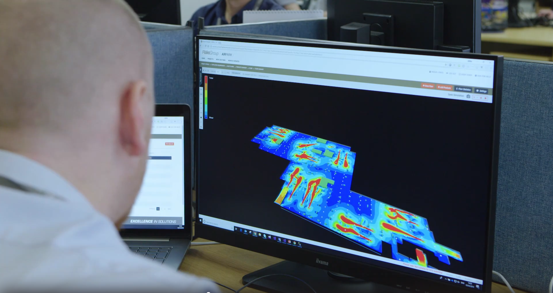 A man looking at a computer screen where a Computational Fluid Dynamics simulation depicts the predicted air flow